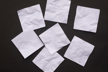 Seven sheets of crumpled white paper on a black background close-up.