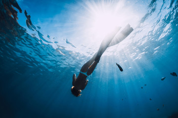 Wall Mural - Attractive woman free diver glides with fins over sandy sea. Freediving in a tropical ocean