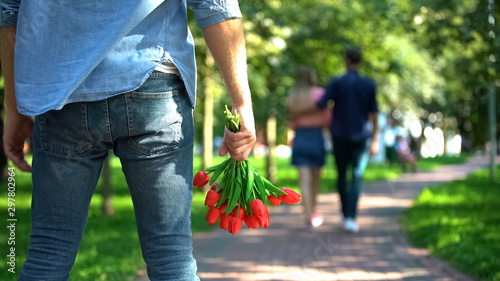 Fotografía Man with flowers looking girlfriend hugging another male, love disappointment