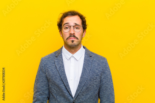 Fotomural young handsome man feeling sad and whiney with an unhappy look, crying with a ne