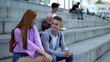 Beautiful redhead girl getting acquainted male teenager on campus stairs, flirt