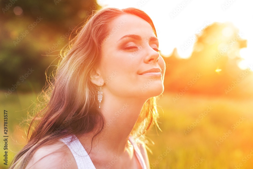 Young woman on field under sunset light - obrazy, fototapety, plakaty 