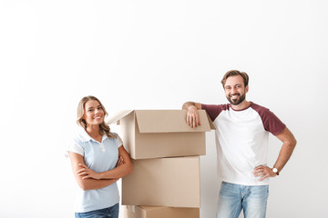 Sticker - Photo of joyful couple smiling and standing near cardboard boxes