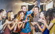© Mirko Vitali - Multiracial happy friend having fun at new year's eve celebration - Young people blowing confetti at after party in night club - Friendship concept on cool entertainment mood - Focus on blue shirt guy