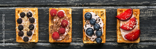 Cuadros en Lienzo Homemade waffles with blueberries, raspberries and peaches on a black wooden rustic background,border