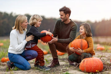 Happy young family in pumpkin patch field