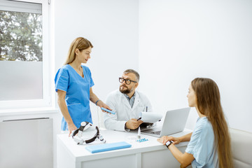 Wall Mural - Young patient at an appointment with otolaryngologists, sitting during the consultation in the bright ENT office interior