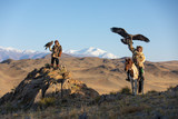 Fototapeta  - Two old traditional kazakh eagle hunters posing with their golden eagle in the mountains. Ulgii, Western Mongolia.