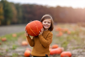 Boy standing on pumpkin in pumpkin patch