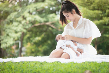 Beautiful Asian young mother  or single mom with new born baby girl are doing activities and relaxing in the park. concept of duties of wife and mother in raising children and family.