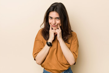 Wall Mural - Young brunette woman against a beige background doubting between two options.