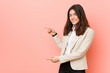 © Asier - Young brunette business woman against a pink background excited pointing with forefingers away.