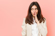 © Asier - Young brunette business woman against a pink background is saying a secret hot braking news and looking aside