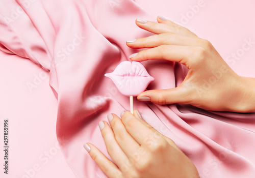 Leinwand Poster Beautiful woman manicure on creative pink background with silk fabric