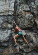 © vitaliymateha - young slim muscular woman rockclimber climbing on tough sport route, climber makes a hard move.