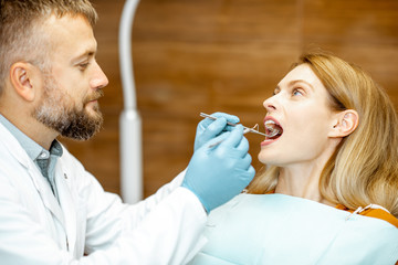 Wall Mural - Beautiful woman as a patient during a teeth inspection with a senior experienced dentist at the clinic