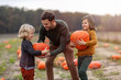 © pikselstock - Father and sons in pumpkin patch field