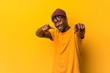 © Asier - Young black man wearing rastas over yellow background cheerful smiles pointing to front.