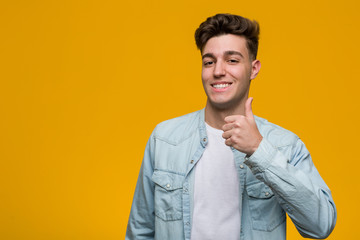 Wall Mural - Young handsome student wearing a denim shirt smiling and raising thumb up
