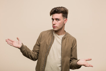 Wall Mural - Young caucasian man wearing a brown jacket doubting between two options.