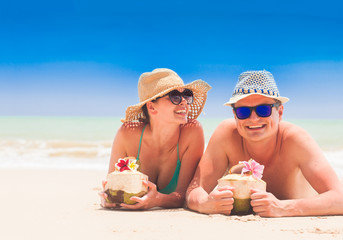 Wall Mural - couple lying at a tropical beach in Barbados and drinking a coconut cocktail