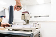 Worker Manipulating Paper Punching Machine In Workshop