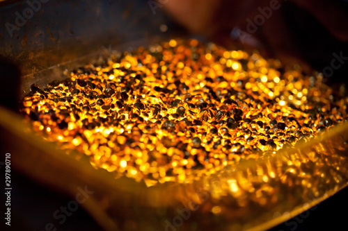 closeup picture of many ingots of melt gold, hot shiny metal pieces glowing