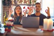 © Krakenimages.com - Young beautiful couple sitting using laptop around christmas decoration at home relax and smiling with eyes closed doing meditation gesture with fingers. Yoga concept.