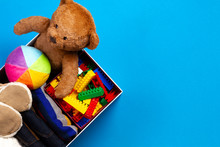 Donation Box With Clothing, Books, Children Toys On Blue Background. Top View