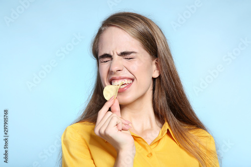 Fotografía Young beautiful girl eating potato chip on blue background
