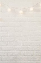 White Brick Wall With Christmas Lights In The Form Of White Balls.