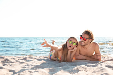 Poster - Happy young couple in sunglasses lying together on beach