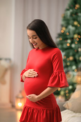 Canvas Print - Happy pregnant woman in room decorated for Christmas. Expecting baby