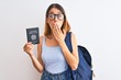 © Krakenimages.com - Beautiful redhead student woman wearing backpack and holding passport of italy cover mouth with hand shocked with shame for mistake, expression of fear, scared in silence, secret concept
