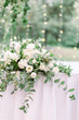 table setting with flower and greenery decoration, covered with tablecloth, outdoors in the garden or forest, small liths bulbs on the blurred background