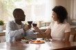© fizkes - Happy smiling african american family couple holding glasses of wine.
