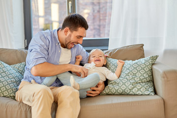 Canvas Print - family, parenthood and fatherhood concept - happy laughing father tickling little baby daughter at home