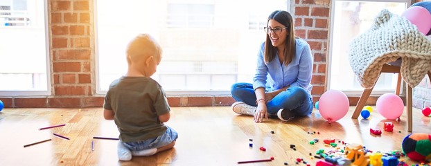 Poster - Young caucasian child playing at playschool with teacher. Mother and son at playroom racing with toy cars