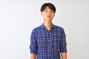 Wall Mural - Young chinese man wearing casual blue shirt standing over isolated white background puffing cheeks with funny face. Mouth inflated with air, crazy expression.