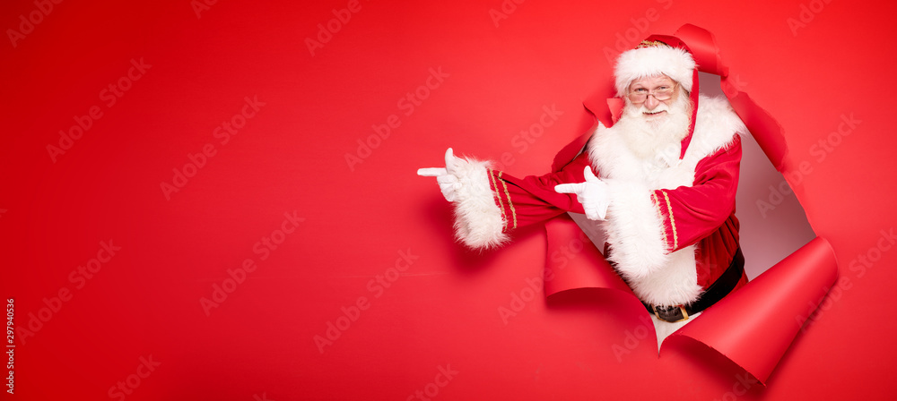 Santa Claus pointing on red empty background. - obrazy, fototapety, plakaty 