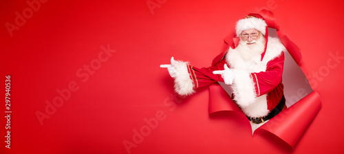 Santa Claus pointing on red empty background. Poster Mural XXL