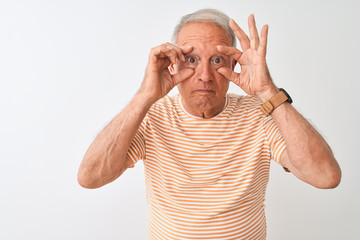 Canvas Print - Senior grey-haired man wearing striped t-shirt standing over isolated white background Trying to open eyes with fingers, sleepy and tired for morning fatigue