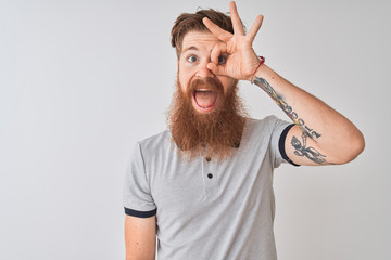 Poster - Young redhead irish man wearing grey polo standing over isolated white background doing ok gesture with hand smiling, eye looking through fingers with happy face.