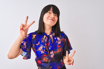 Wall Mural - Young beautiful chinese woman wearing summer floral t-shirt over isolated white background smiling looking to the camera showing fingers doing victory sign. Number two.