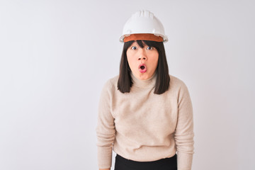 Wall Mural - Young beautiful Chinese architect woman wearing helmet over isolated white background afraid and shocked with surprise expression, fear and excited face.