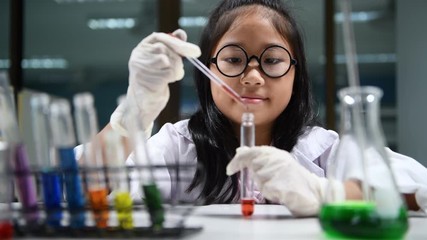 Wall Mural - cute little girl wearing lab coat making experiment in chemical laboratory, ecucation and science co