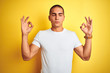 © Krakenimages.com - Young caucasian man wearing casual white t-shirt over yellow isolated background relax and smiling with eyes closed doing meditation gesture with fingers. Yoga concept.