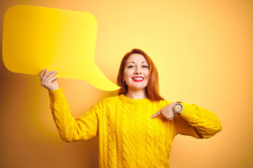 Sticker - Young beautiful redhead woman holding speech bubble over yellow isolated background with surprise face pointing finger to himself