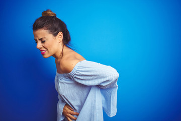 Canvas Print - Young beautiful woman wearing bun hairstyle over blue isolated background Suffering of backache, touching back with hand, muscular pain