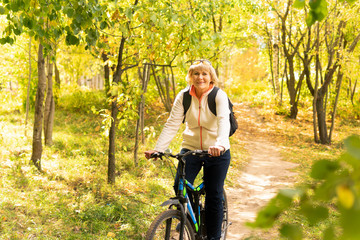 A woman on a Bicycle rides through the autumn Park among the trees.